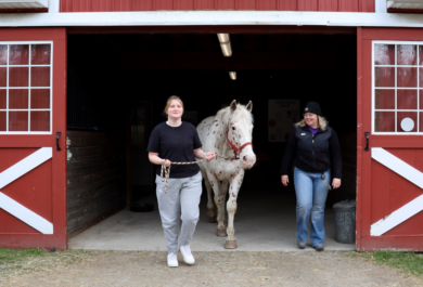 Student Zoe walks her horse partner Gandalf out of the horse barn during a specialized therapy small group session of Hoof Harmony